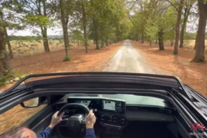 Vue dynamique depuis le toit ouvrant de la Renault 4 E-Tech plein Sud sur un chemin forestier